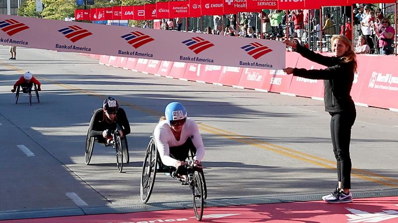 a female wheelchair racer crosses the finish line