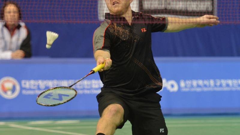 a male Para badminton player goes for a shot