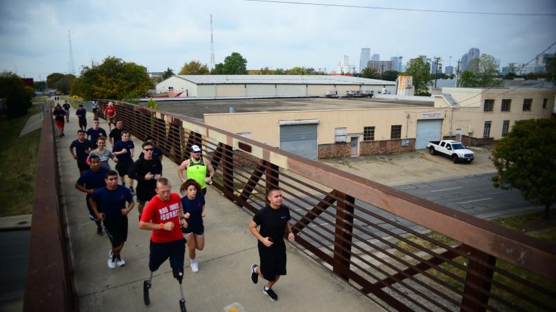 Double amputee running with group of people running behind him