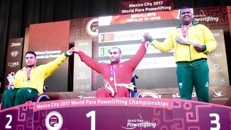 three male powerlifters on the podium