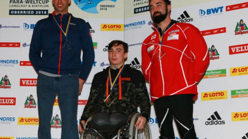 three male sit skiers on the podium