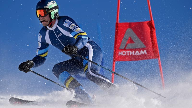 a male vision impaired skier rounds a gate