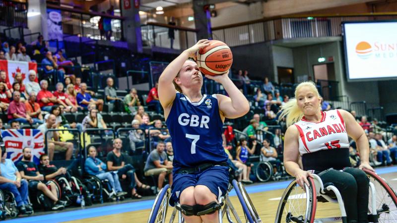 British female basketball player shoots the ball while Canadian player tries to defend