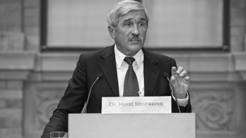 Black and white photo of a man in suit speaking at a podium