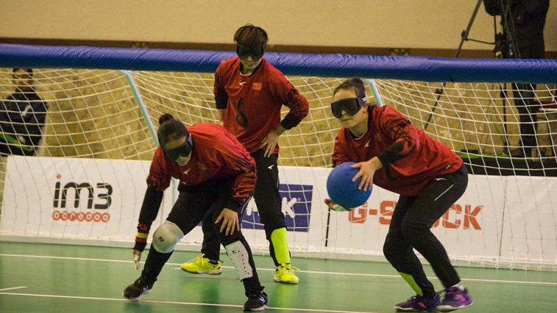 three female Chinese goalball players talking in front of the goal