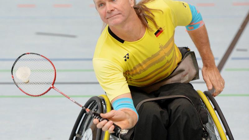 male Para badminton player Thomas Wandschneider reaches down to hit a forehand
