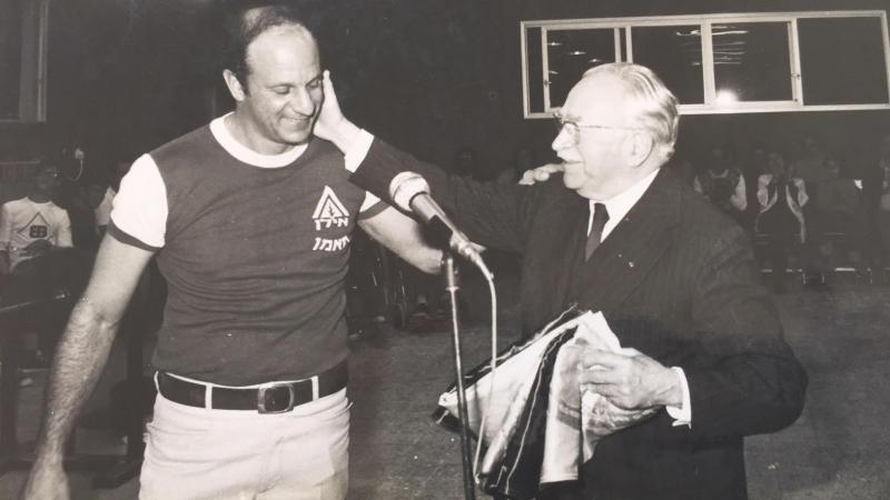 Reuven Heller puts his arm on the shoulder of Sir Ludwig Guttman who is touching his face