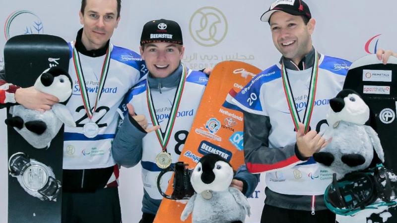 Three men with helmets in an indoor snowboard track