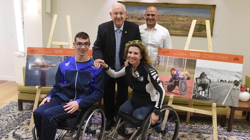 two people in wheelchairs seated next to two people standing