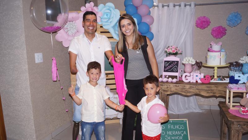 Paralympic swimmer Daniel Dias and his wife holding up a little pink swimsuit, with their two boys standing in front