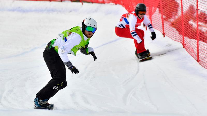 two male Para snowboarders racing down the slope head to head
