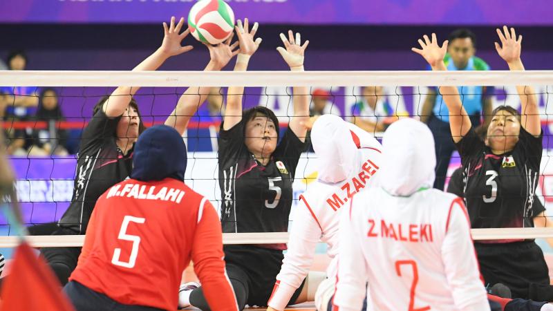 two female sitting volleyball teams contesting the ball on court