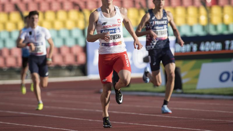 A male sprinter runner ahead of two other competitors