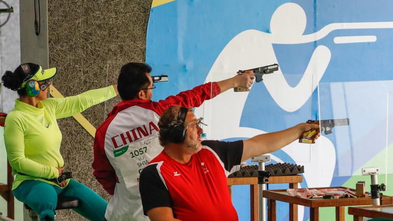 A one-legged woman and two men competing at a shooting range