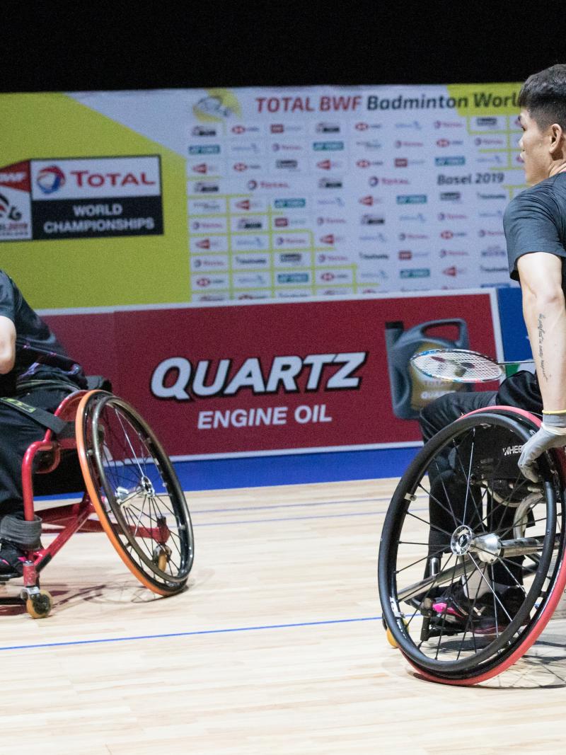 Two male Chinese badminton players in wheelchairs celebrate a point