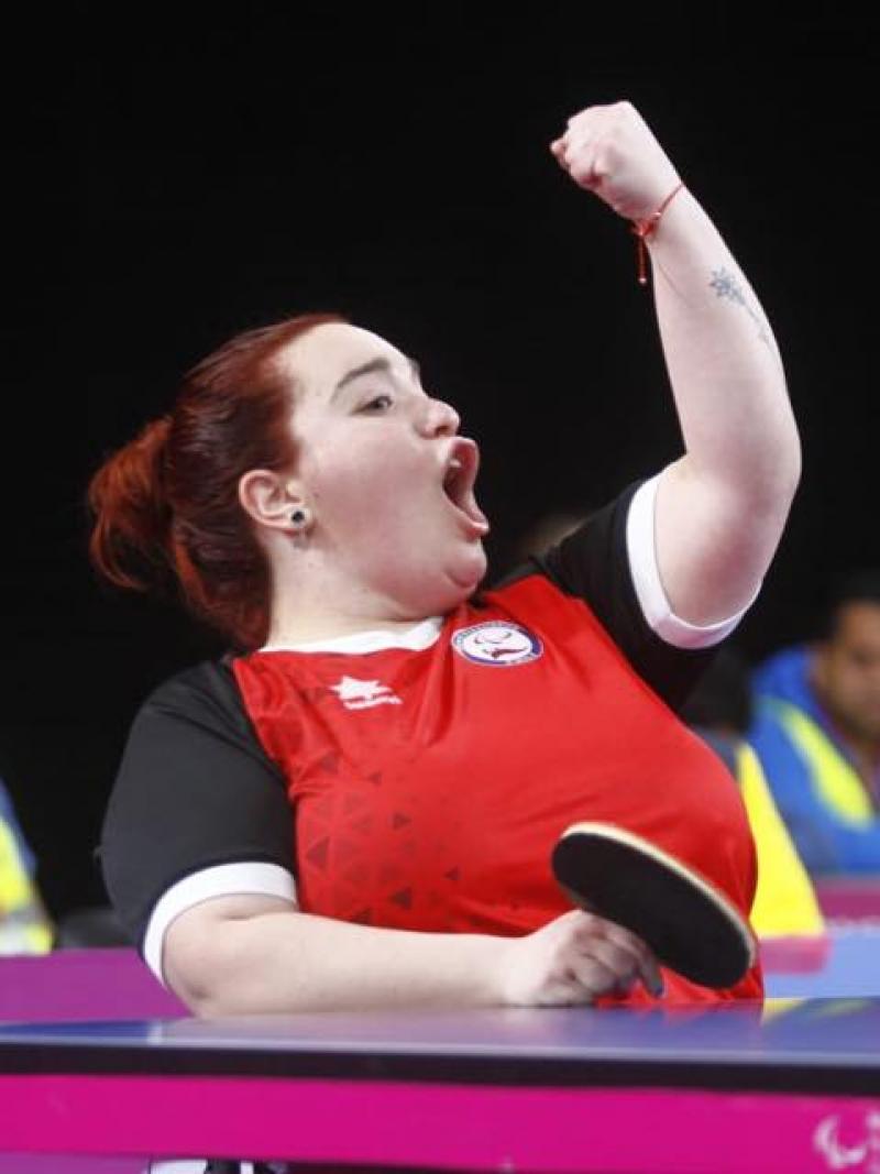 a female wheelchair table tennis player punches the air in victory