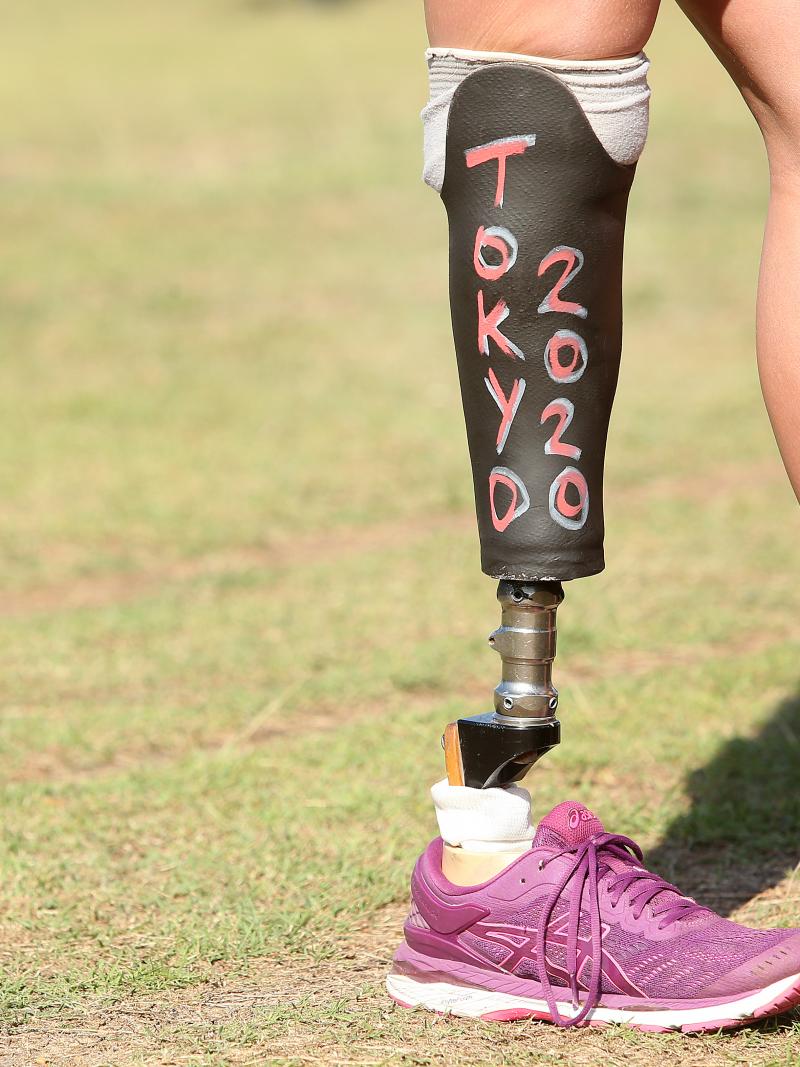 a woman standing with a prosthetic leg that has Tokyo 2020 written on it