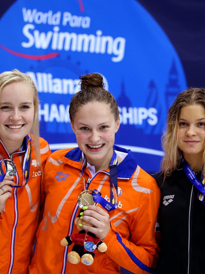 three female Para swimmers on the podium holding up their medals