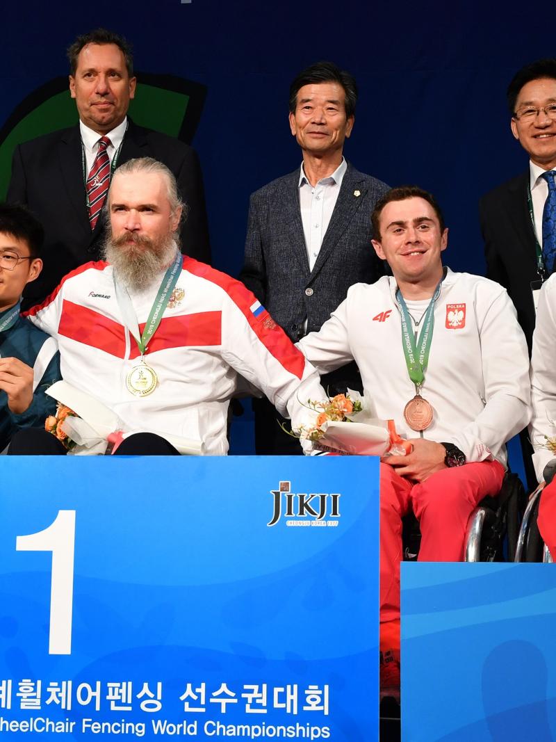 Four men in wheelchairs in a podium with three standing men behind them