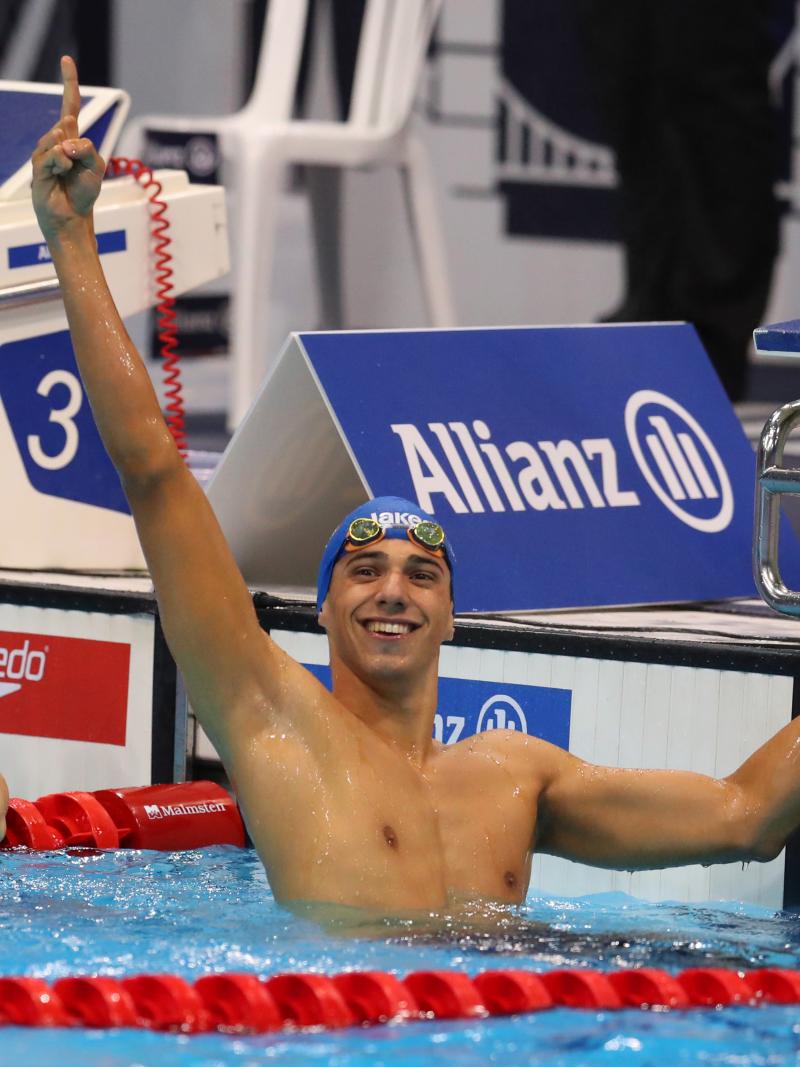 a male Para swimmer raises his arm in celebration in the pool