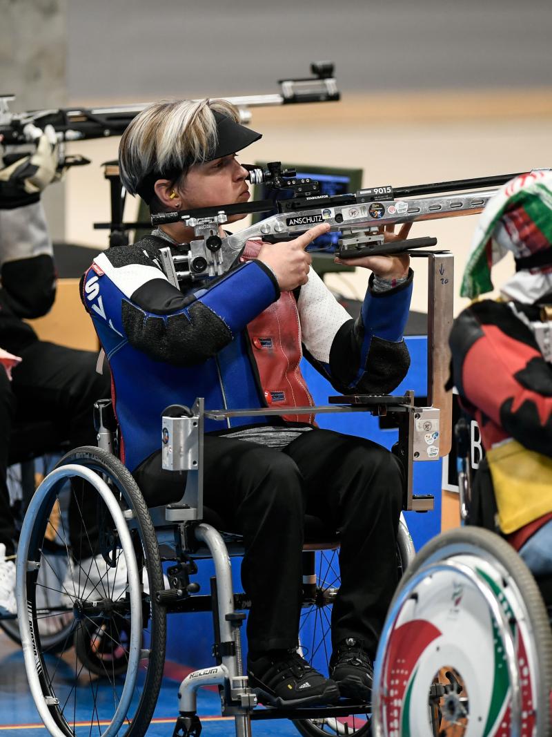 Three female shooters in wheelchairs competing with rifles