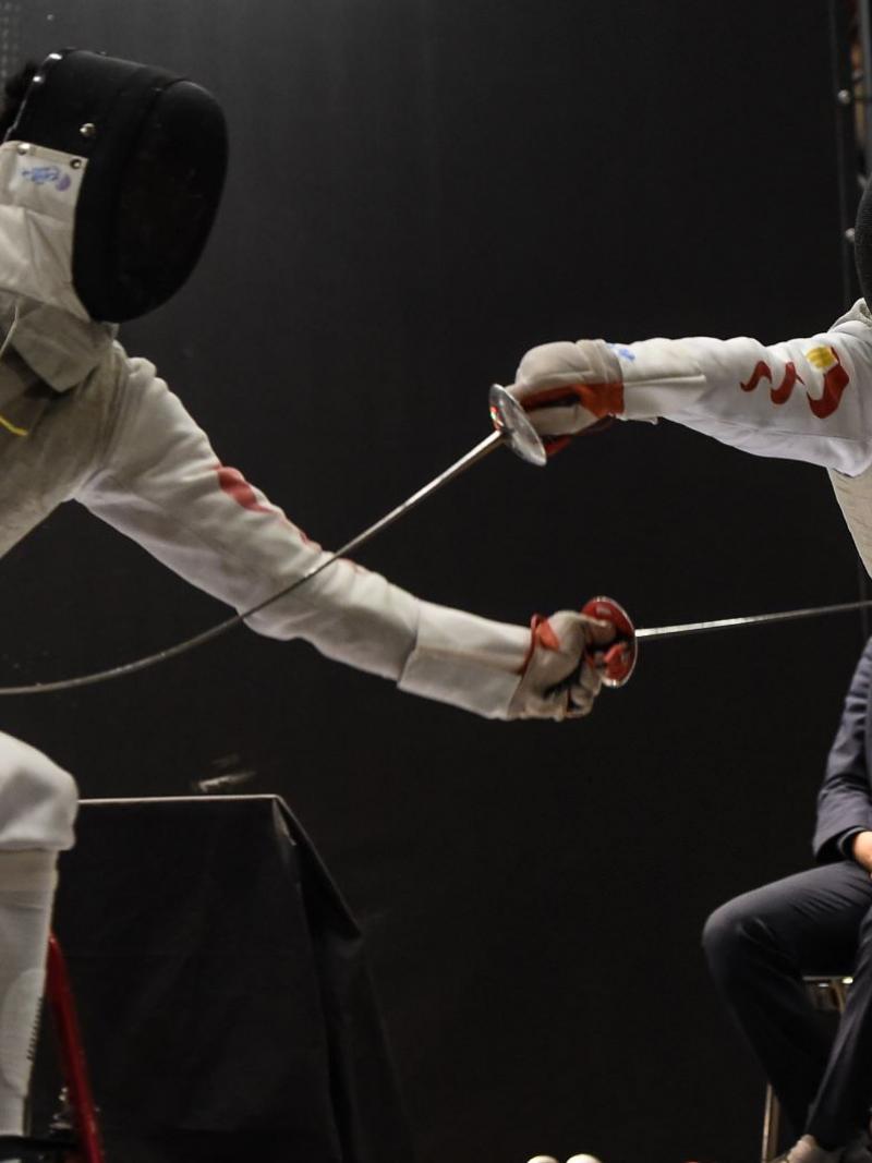Two male Chinese wheelchair fencers battling on the piste