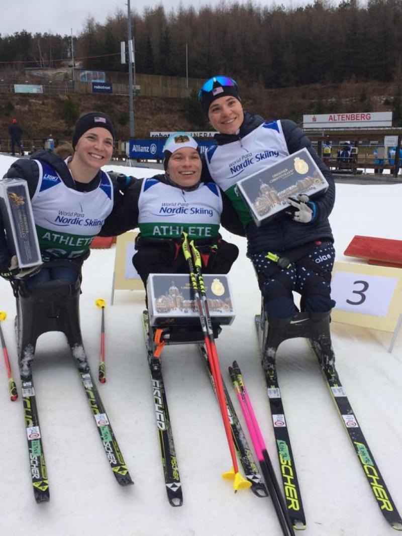 Three female sit-skiers posing with their trophies