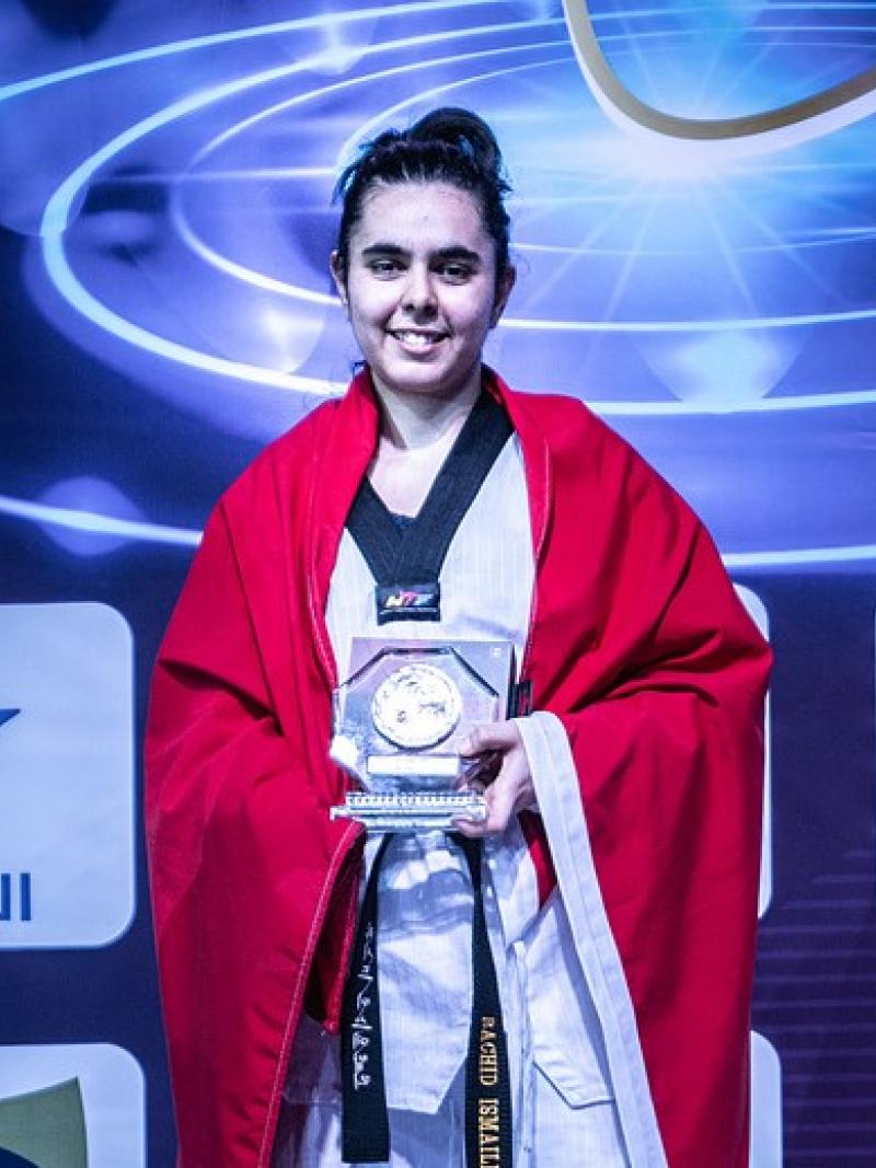 Female taekwondo fighter smiles holding prize