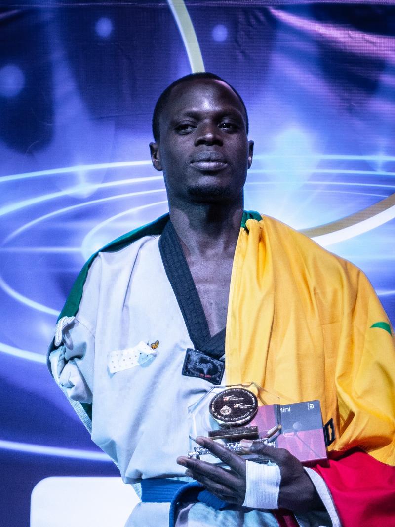 Male African taekwondo player smiles on podium