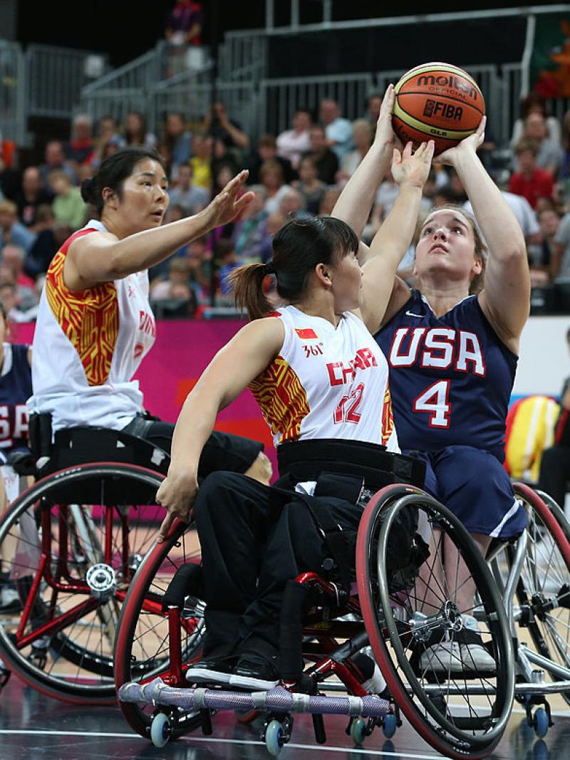 US female wheelchair basketball player shoots the ball while being double teamed