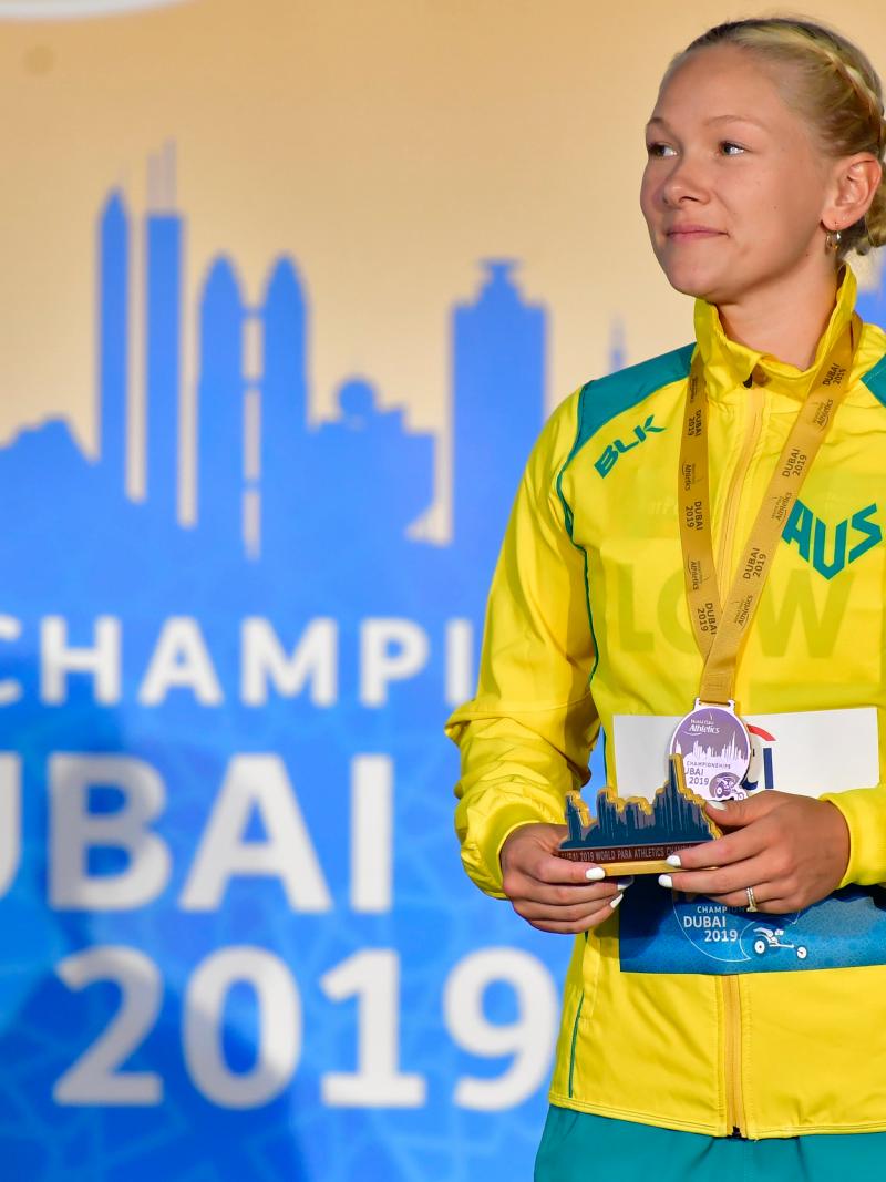 A woman with a medal standing on a stage