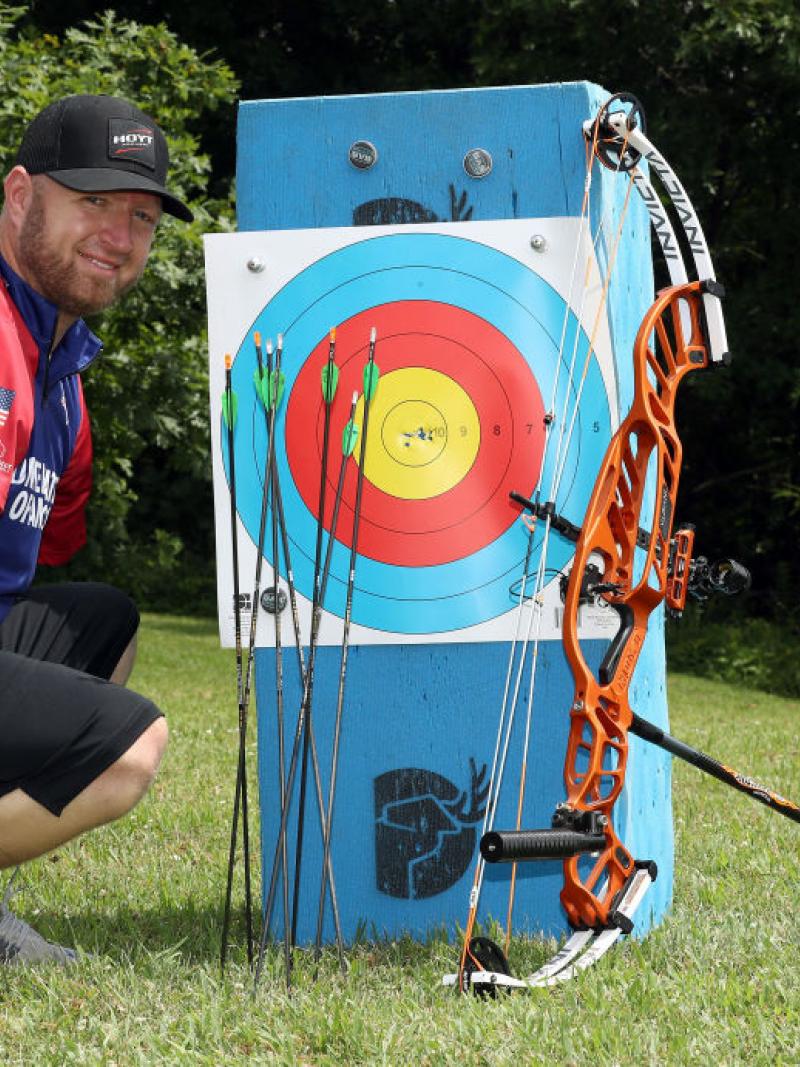 Male archer without arms poses next to his targets