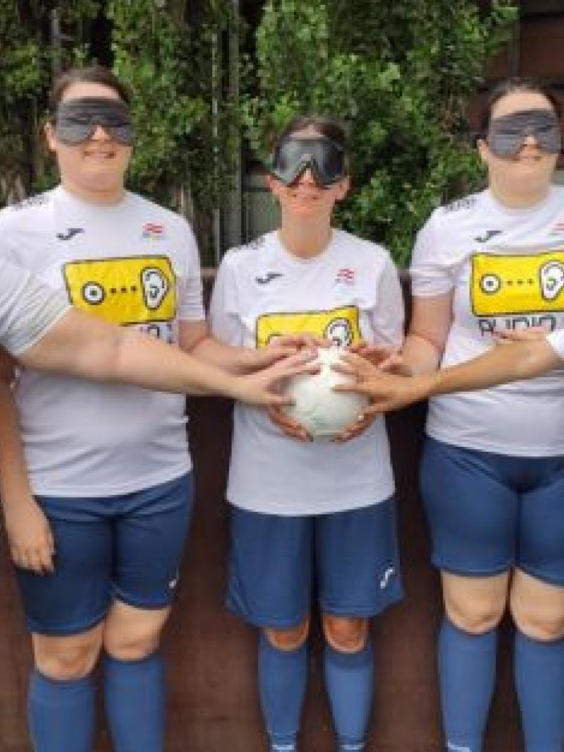 Five blind female footballer all holding a football together