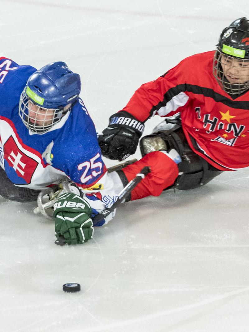 A Para ice hockey player with the uniform of Slovakia playing against another player from China