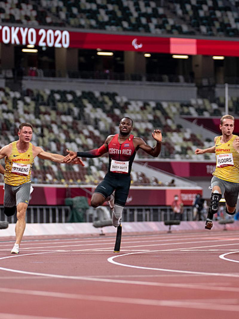 Six men with prosthetic legs crossing the line in a 100m race