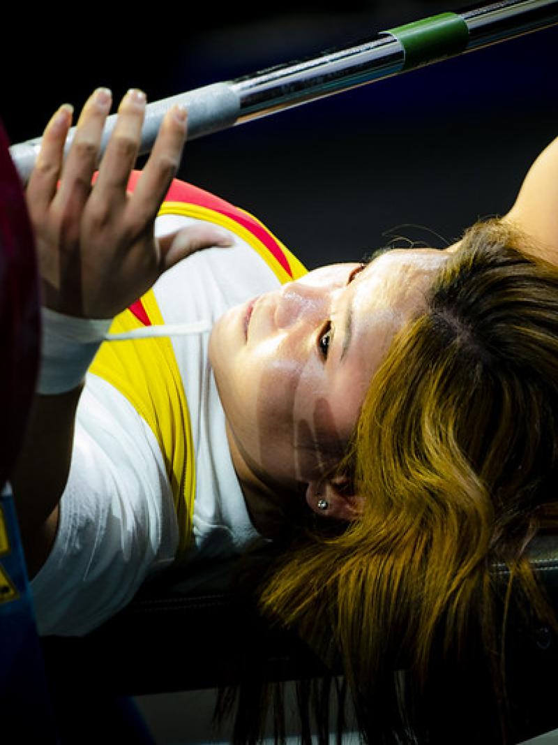 A woman putting her hands around a bar on a bench press