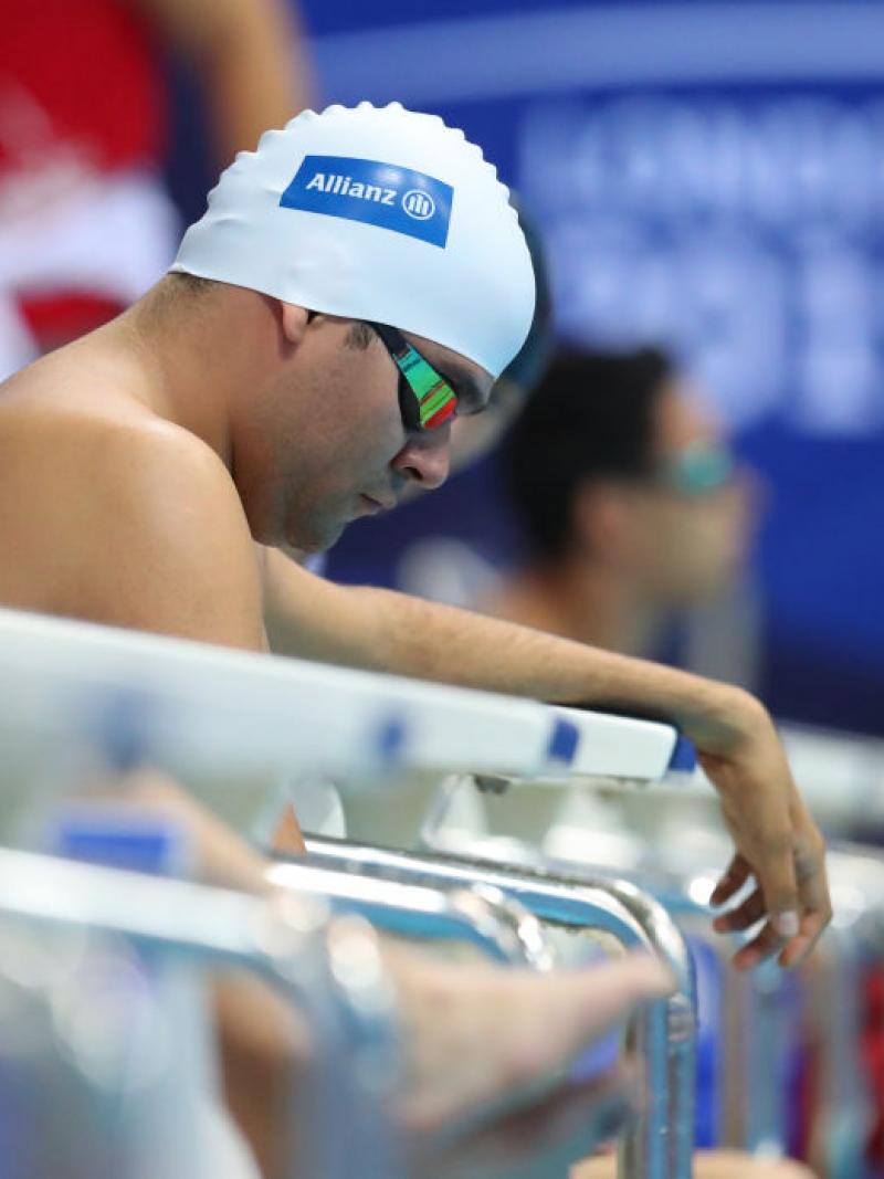 A man sits on the edge of the pool waiting for his race to start