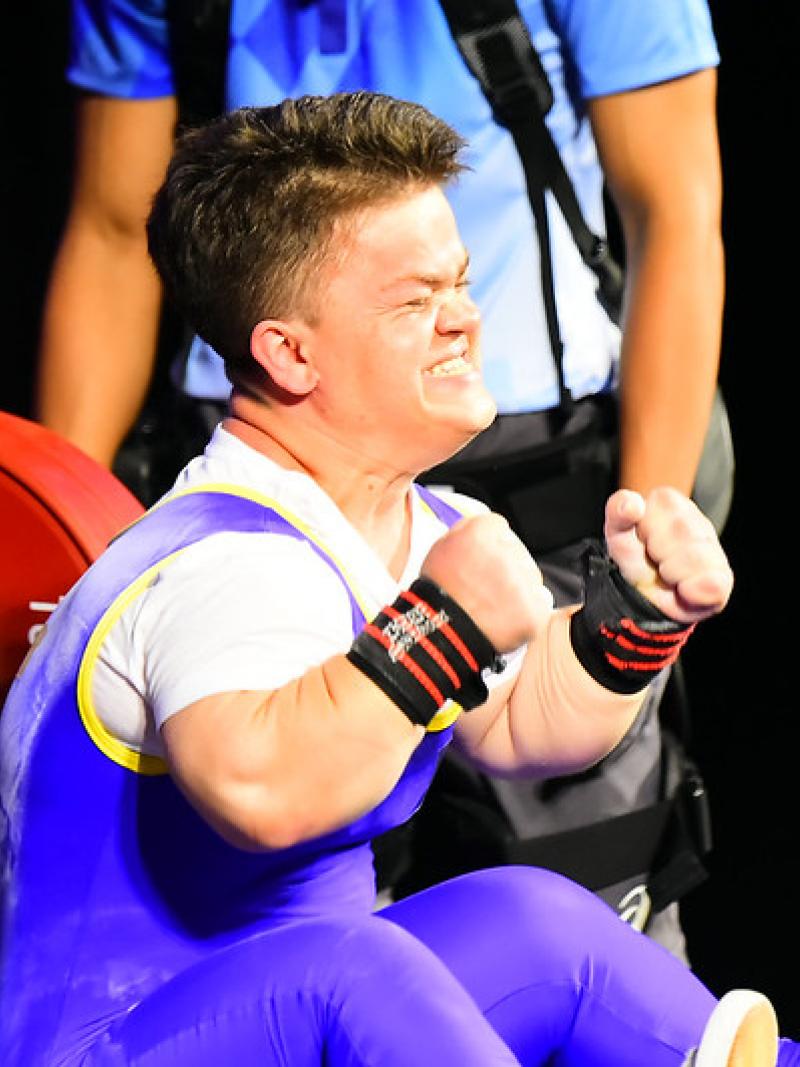 A short stature woman celebrating on a bench press