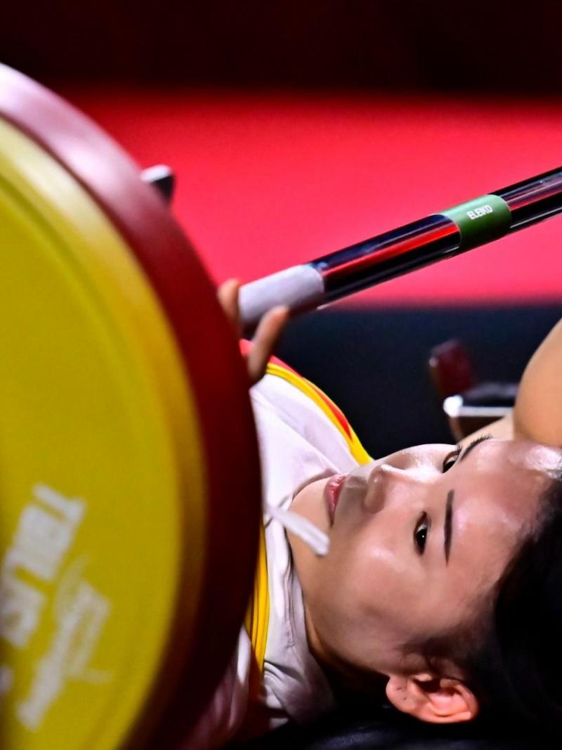 A woman on a bench press looking at the bar