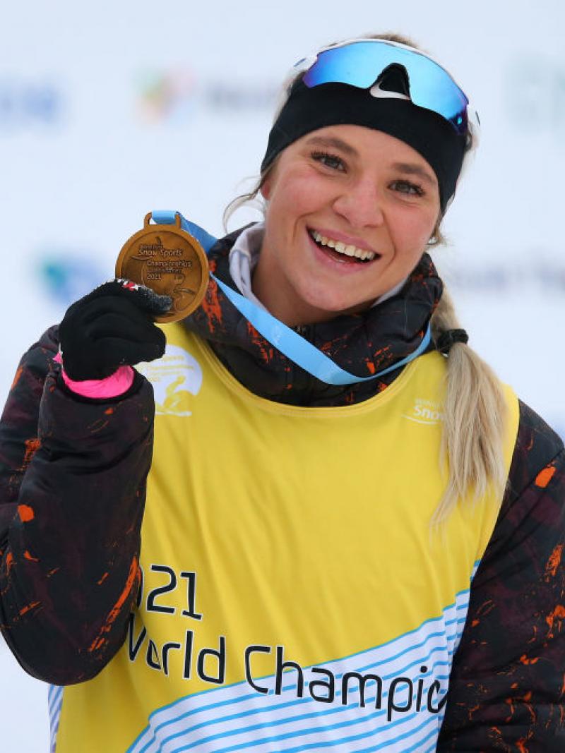 A woman smiling and showing her gold medal