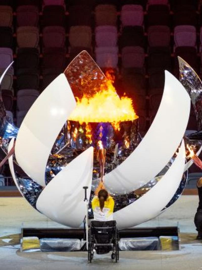 Three athletes on wheelchairs light a sphere-shaped cauldron during the Opening Ceremony of the Tokyo 2020 Paralympic Games.