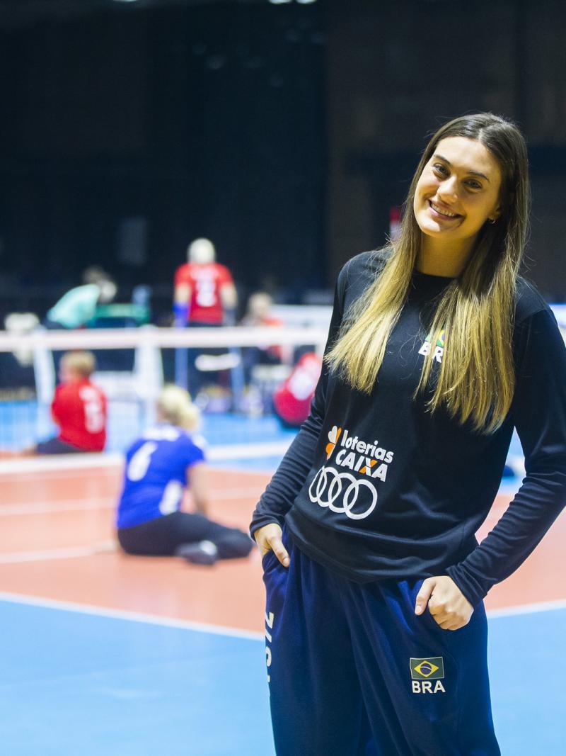 A female athlete smiling in front of a sitting volleyball court