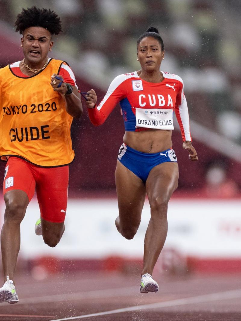 A female Para athlete runs with her male guide runner