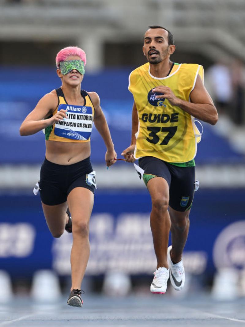 A female runner wearing green blindfolds competes with her guide runner