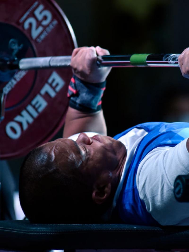 A male Para powerlifter lifts weight during a competition