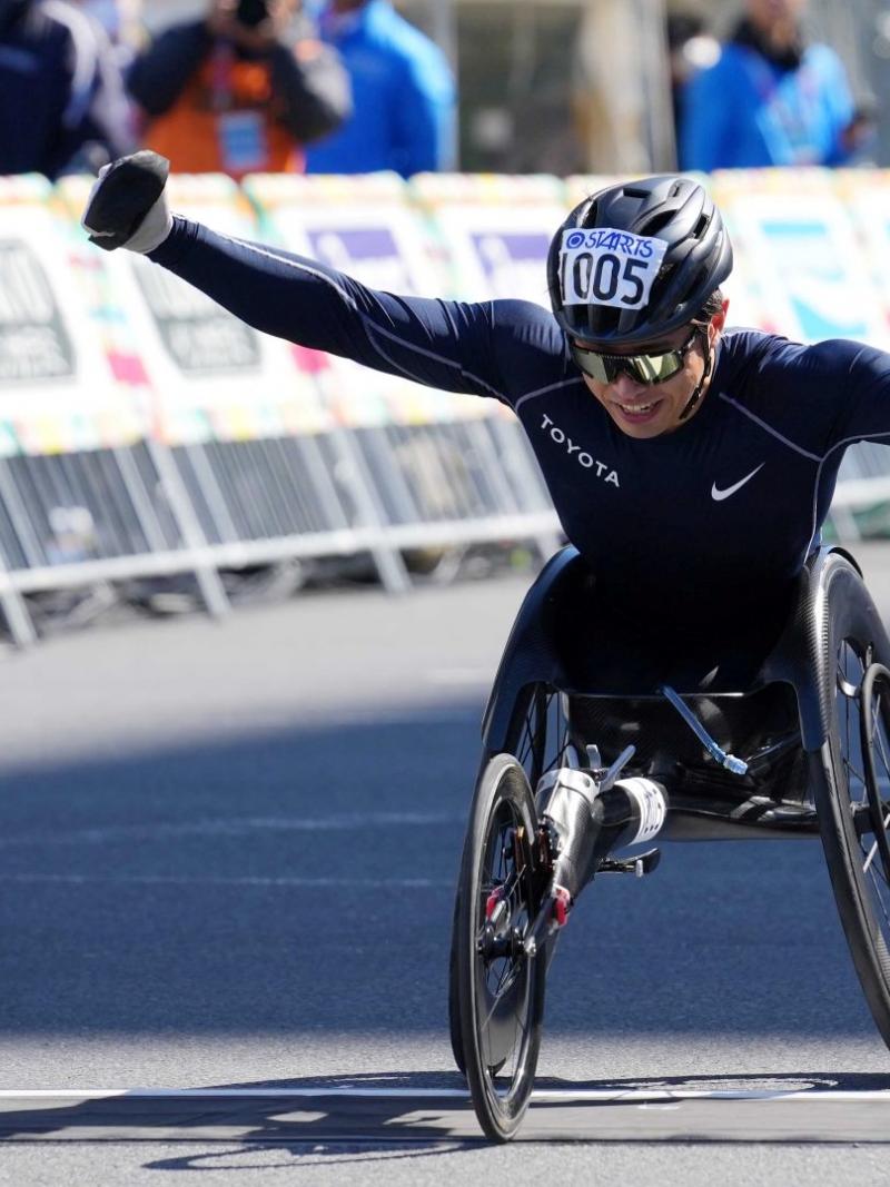 A male wheelchair racer opening his arms in a street marathon