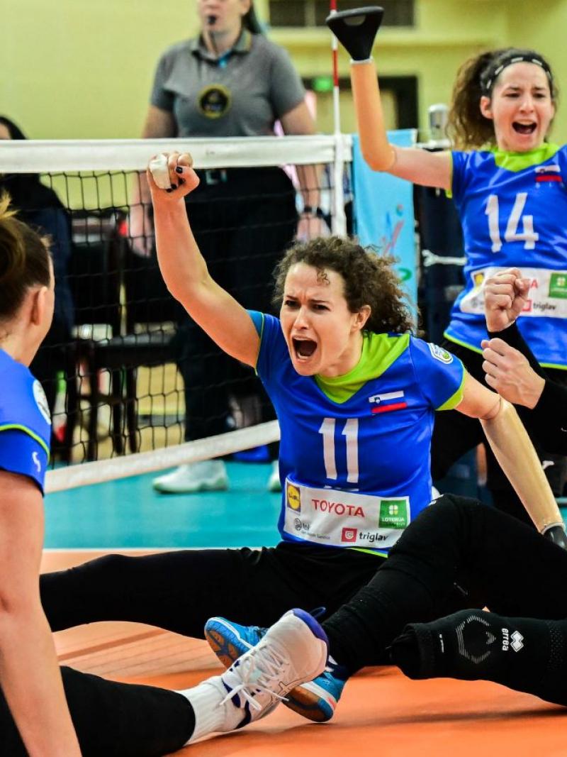 Four female athletes on Slovenia's sitting volleyball team celebrates on court during the final Paralympic qualification tournament.
