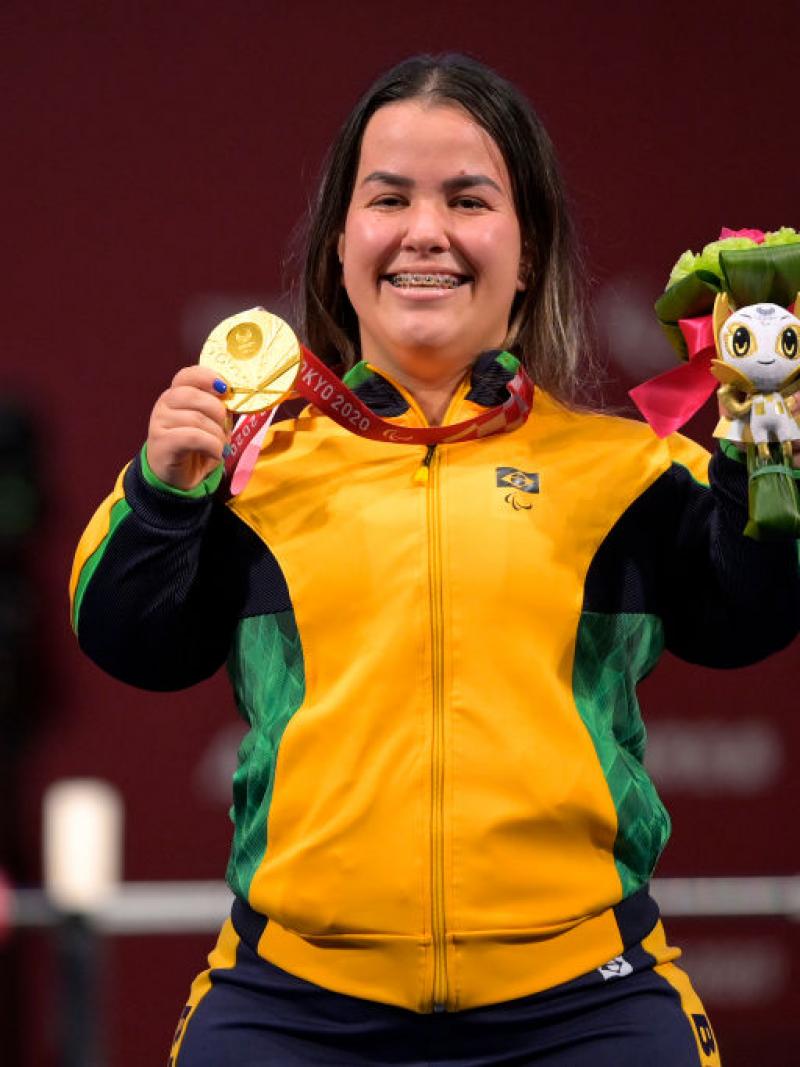 A female Para powerlifter poses for a photo after receiving a gold medal.