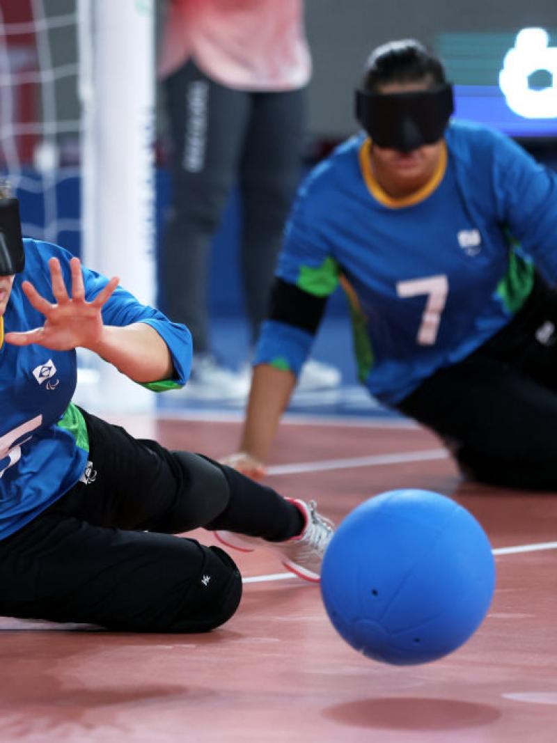 A female athlete tries to block a ball in front of the goalball net