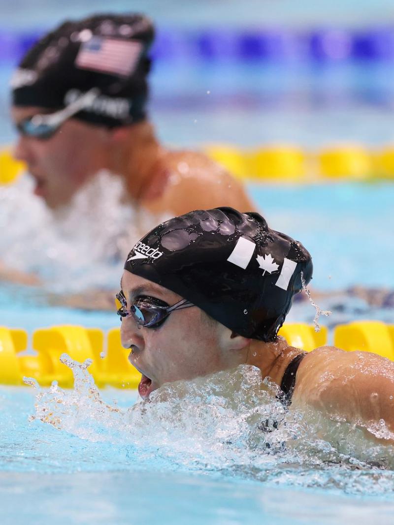 A female swimmer with another swimmer in the background in a race